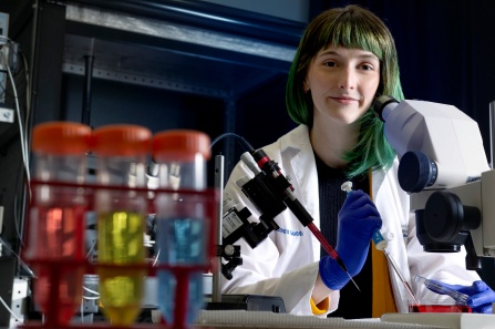 Student in research lab using pipettes.