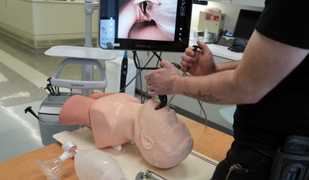 A user demonstrates video laryngoscopy on an airway trainer.