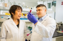 Two scientists examining a vial in a lab.