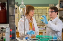 Two scientists working with test tubes and vials in a chemistry lab.