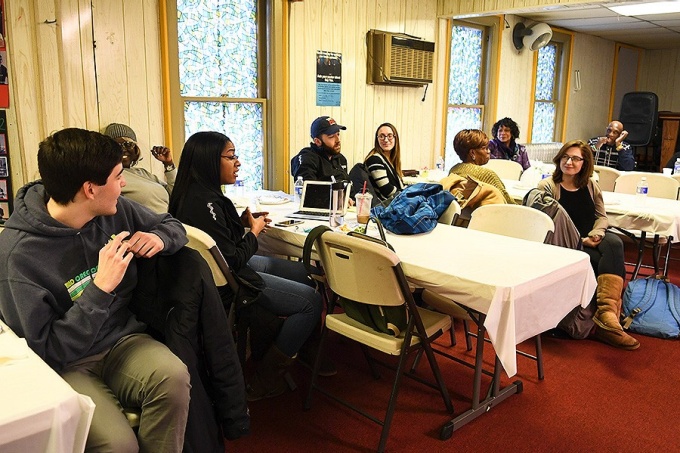 Medical students and members of the Hopewell Baptist church sit at tables talking. 