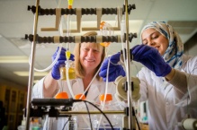 Two scientists in a laboratory working with a device with tubes. 