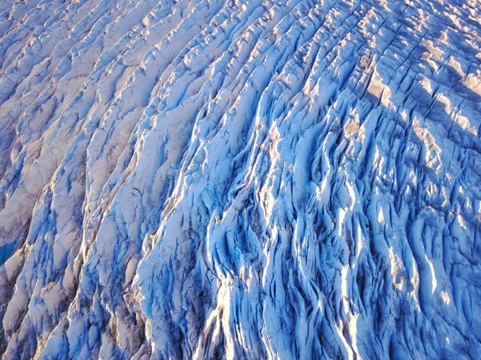 An aerial view of an ice sheet, showing large cracks called crevasses. 