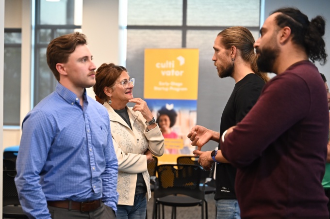 Four people standing around talking to one another in Cultivator's office. 