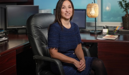 Beth Smith in a blue shirt is sitting in her office. 
